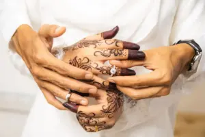 Hands exchanging wedding rings with henna designs.
